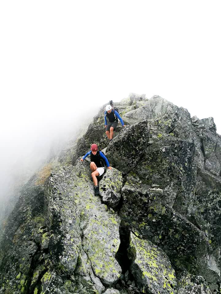 skała na którą wspina się dwoje ludzi w kaskach, z tyłu mgła, wspinaczka na Lodowy Szczyt